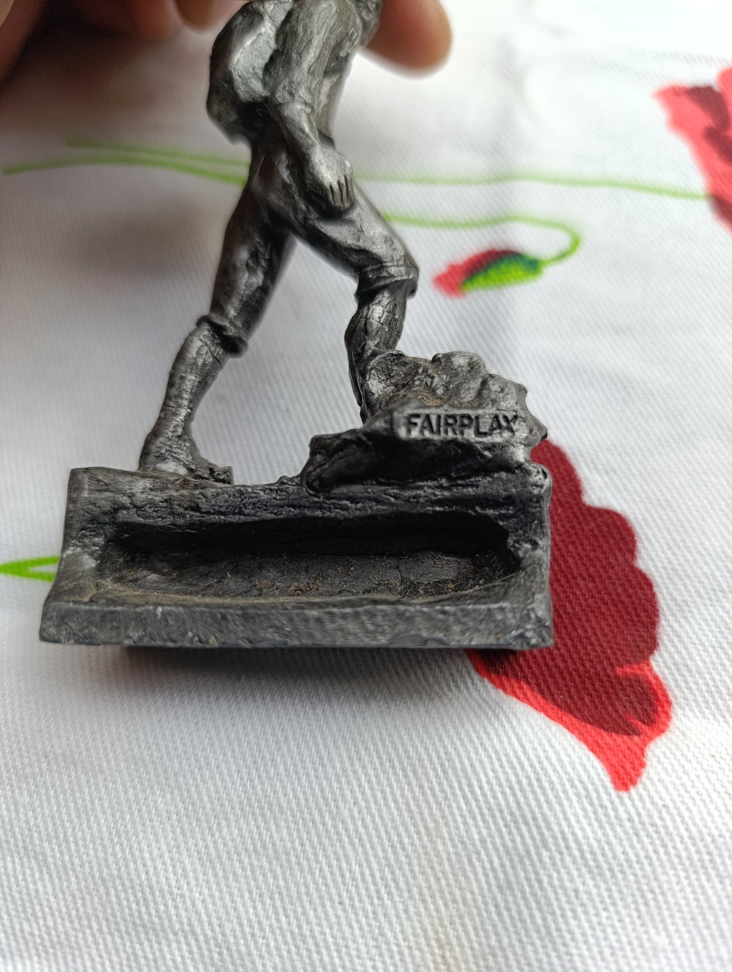 Petite statuette en métal patiné représentant un joueur de football, posant le pied sur un ballon.