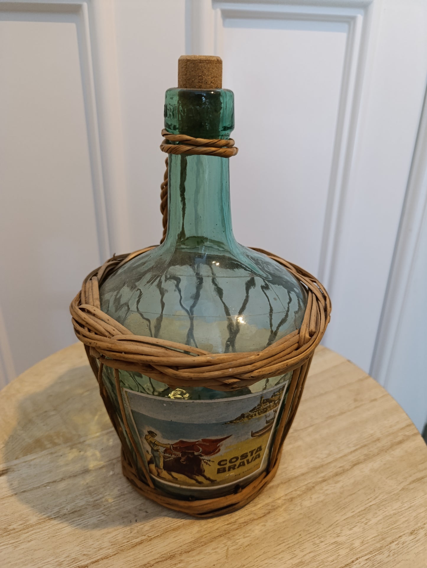 Bouteille en verre verte Costa Brava avec anse en osier tressé