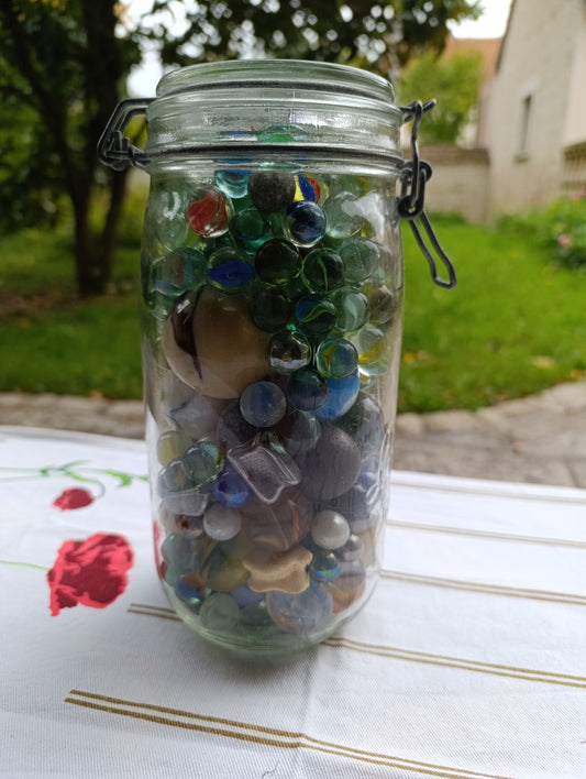 Bocal ancien en verre avec fermeture métallique, rempli de billes multicolores.