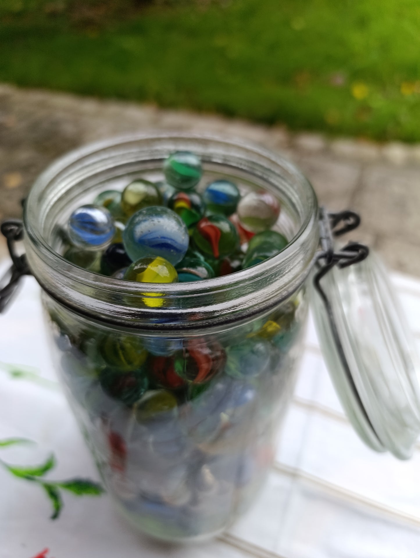 Bocal ancien en verre avec fermeture métallique, rempli de billes multicolores.