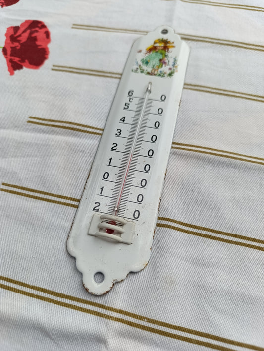 Thermomètre mural vintage en métal émaillé, décor d’une fillette au chapeau et robe verte entourée de fleurs.