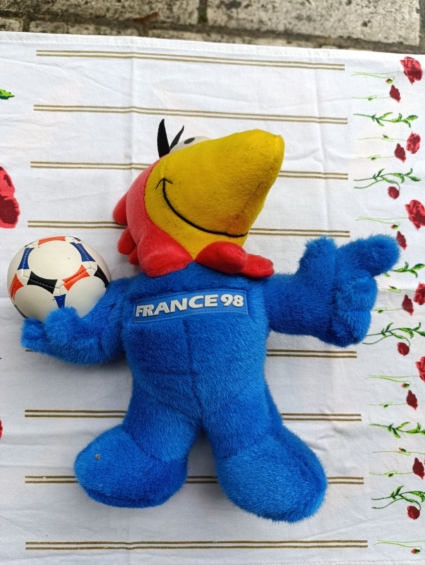 Peluche officielle France 98 représentant la mascotte du Mondial, en position debout tenant un ballon.