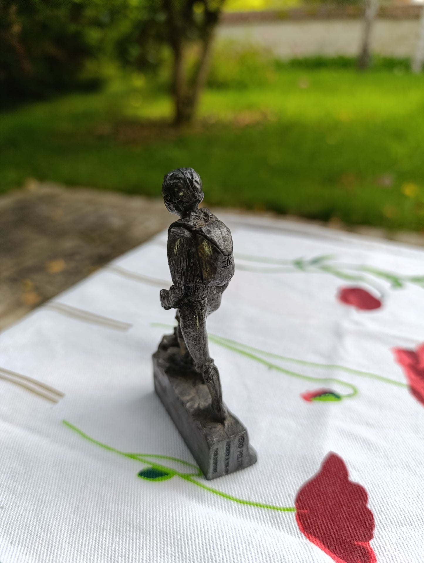 Petite statuette en métal patiné représentant un joueur de football, posant le pied sur un ballon.