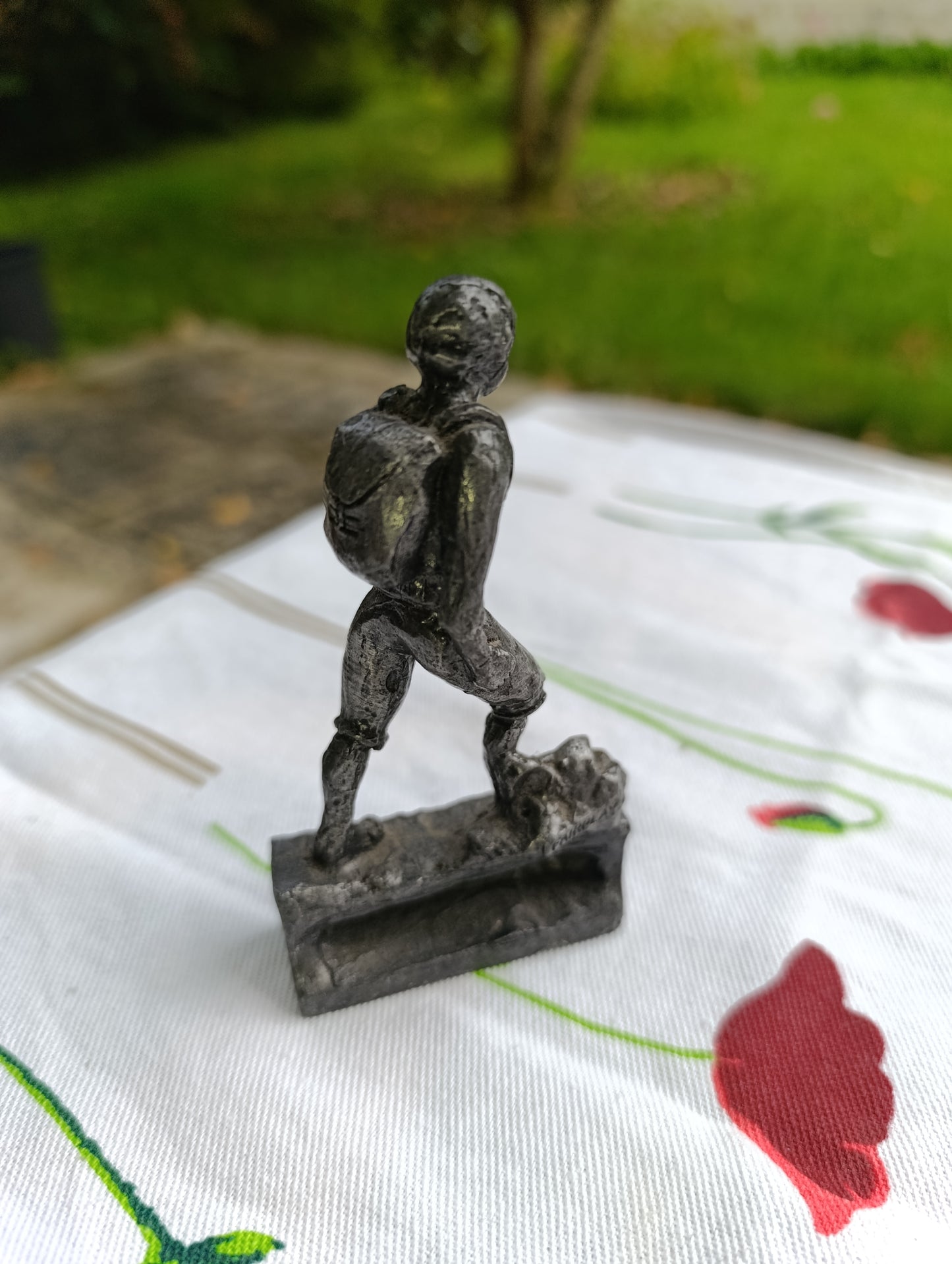 Petite statuette en métal patiné représentant un joueur de football, posant le pied sur un ballon.