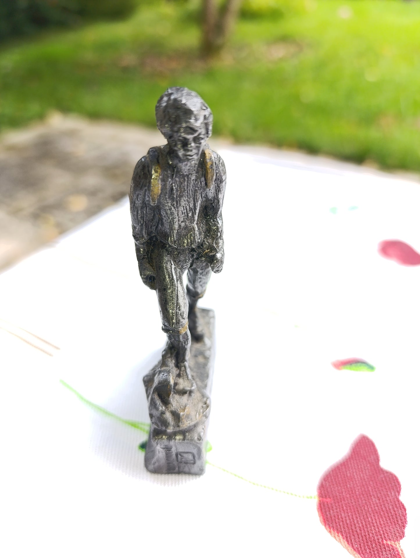 Petite statuette en métal patiné représentant un joueur de football, posant le pied sur un ballon.