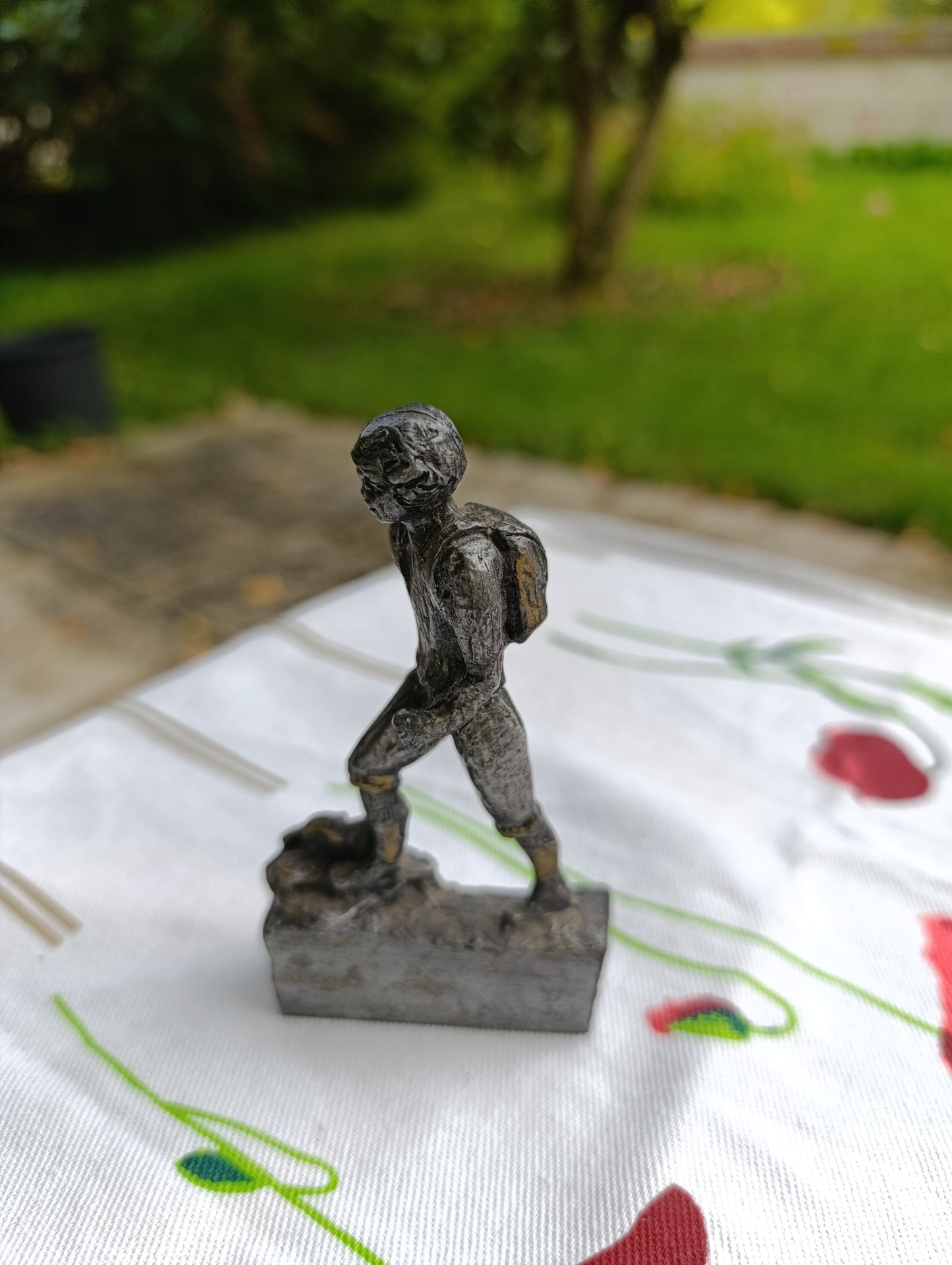 Petite statuette en métal patiné représentant un joueur de football, posant le pied sur un ballon.