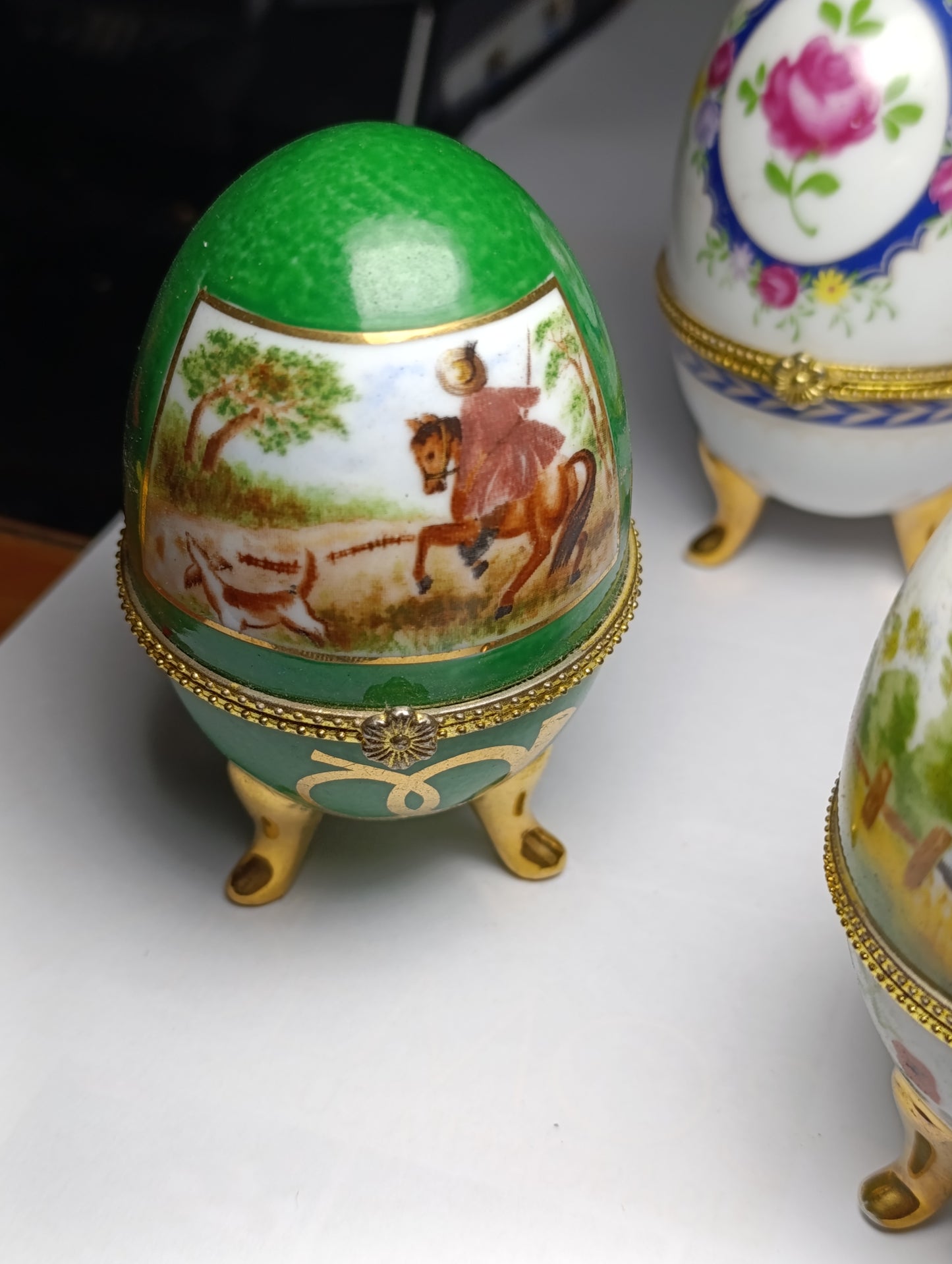 Lot de 4 œufs décoratifs en porcelaine style Fabergé sur pieds dorés