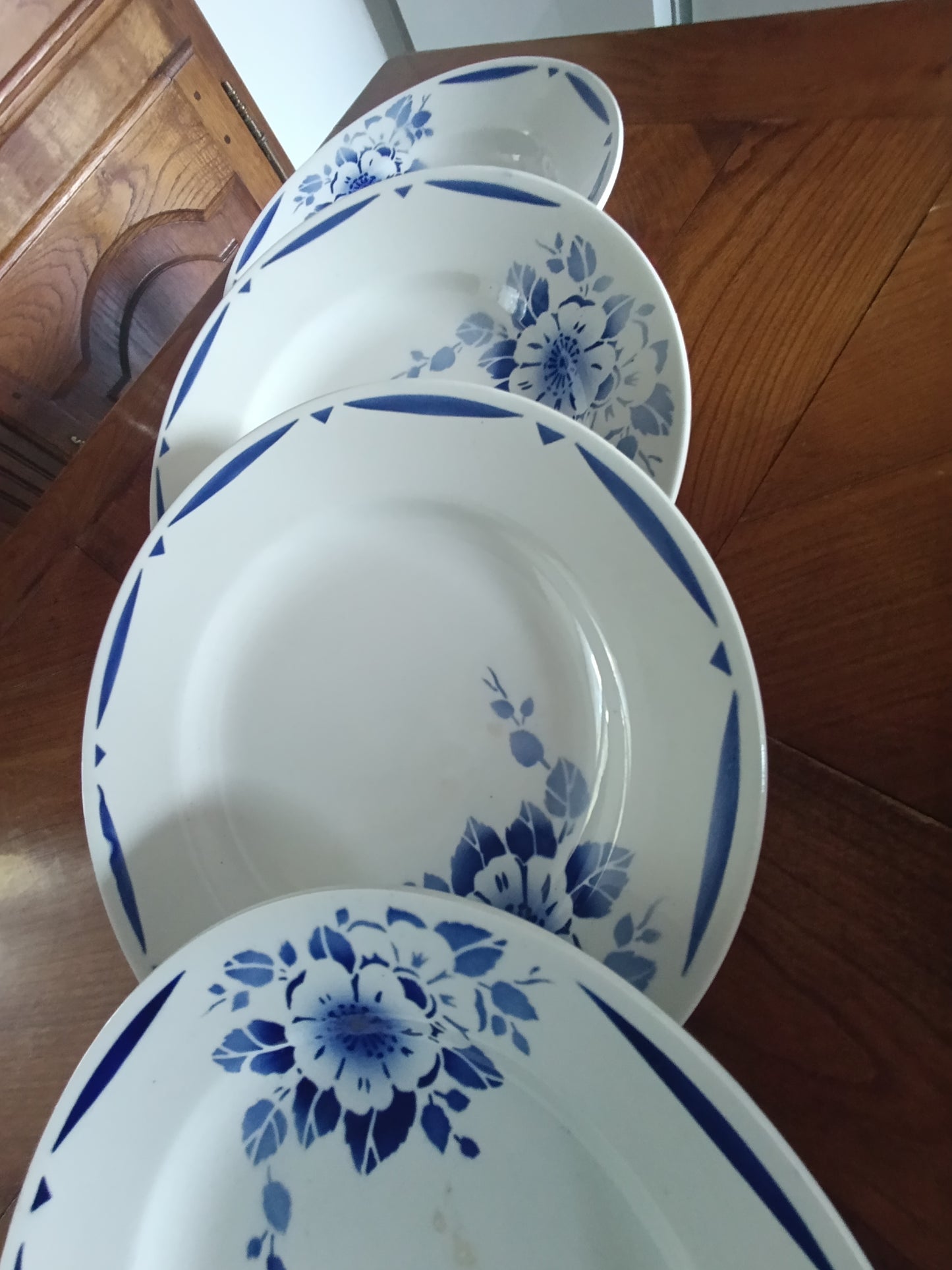 Lot de 4 assiettes creuses anciennes en faïence blanche décor floral bleu.